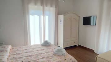 Ein Schlafzimmer mit Bett, Kleiderschrank, Fernseher und einer Chandelier.