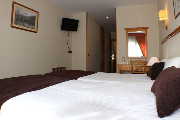 A hotel room with two beds, a television, a desk with a chair, and a mirror. - Hotel Meta (Pas de la Casa)
