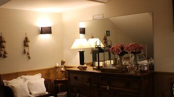 Una habitación acogedora con un aparador de madera, un banco con cojines blancos, un espejo y una lámpara de pared.