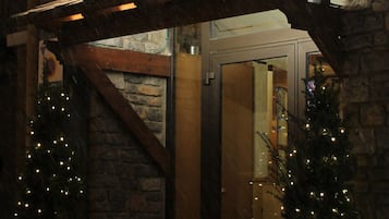 Entrada de un hotel con un cartel que dice "Meta Hotel", flanqueada por dos árboles de Navidad iluminados.