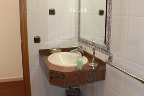 Un baño con lavamanos, espejo y paredes de azulejos.