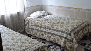 A room with two beds, a window with curtains, and patterned floor tiles. - Island Charm Apartments (Roatan)