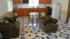 A kitchen with wooden cabinets, a dining table with chairs, and a refrigerator. - Island Charm Apartments (Roatan)