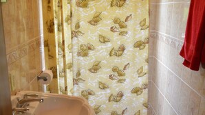 A bathroom with a sink, toilet, and shower curtain. - Island Charm Apartments (Roatan)