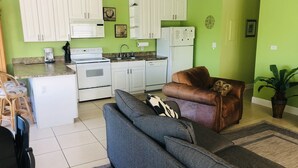 A compact living space with a kitchenette, a sofa, a brown leather chair, and a potted plant. - 2 Incredible Waterfront Homes - One Low Price! (Marathon)
