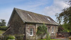 A stone house with a sloped roof, a small window, and a door. - The Old Stables At Westerton (Crieff)
