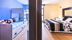 A room with bunk beds on one side and a single bed on the other, wooden flooring, and a window with a view. - Casa Sony El Cotillo (El Cotillo)