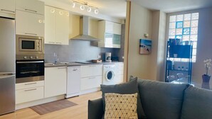A modern kitchen with built-in appliances, a dining area with a glass table, and a view of the sea through a window. - Casa Sony El Cotillo (El Cotillo)