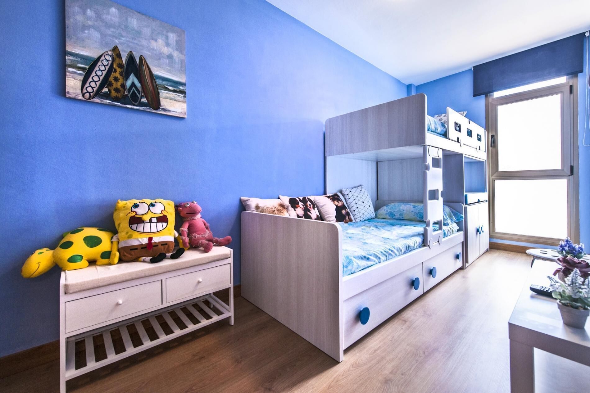 Une chambre d’enfant avec des lits superposés, une commode et une fenêtre donnant sur un beau paysage.