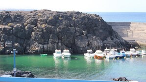 A rocky coastline with boats docked at a harbor. - Casa Sony El Cotillo (El Cotillo)