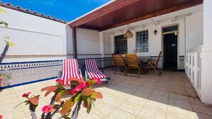 A patio with two sun loungers, a table with chairs, and a tiled floor. - Casa Sony El Cotillo (El Cotillo)