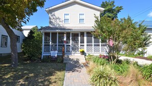 A two-story house with a front porch, a 'For Rent' sign, and a small garden.