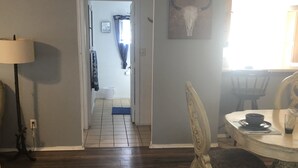 A room with a wooden floor, a dining table with chairs, a lamp, and a wall-mounted artwork. - Relaxing fishing and hunting getaway 1 bock from the water (Port Mansfield)