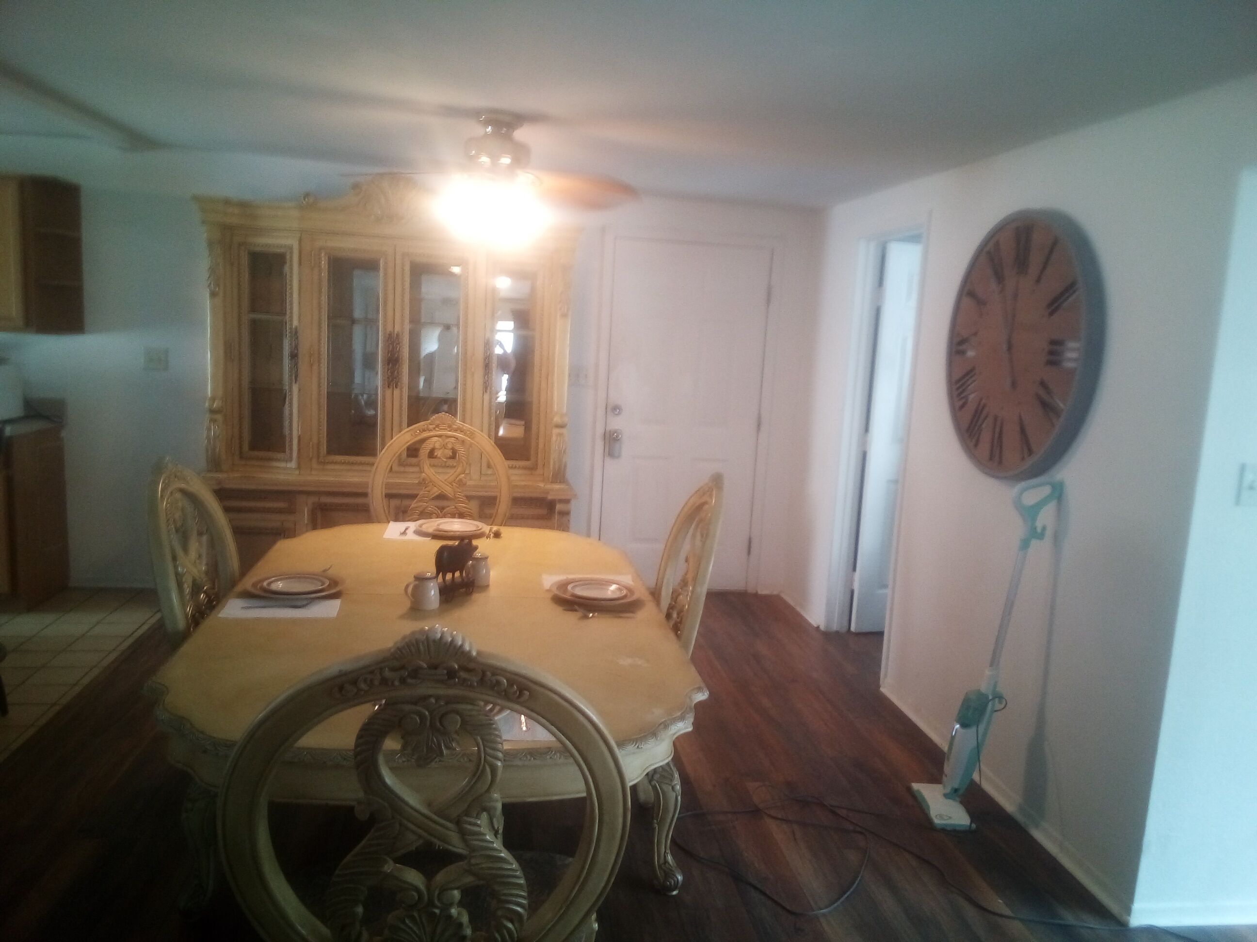 Comedor con mesa de madera, sillas, candelabro, reloj y aparador.