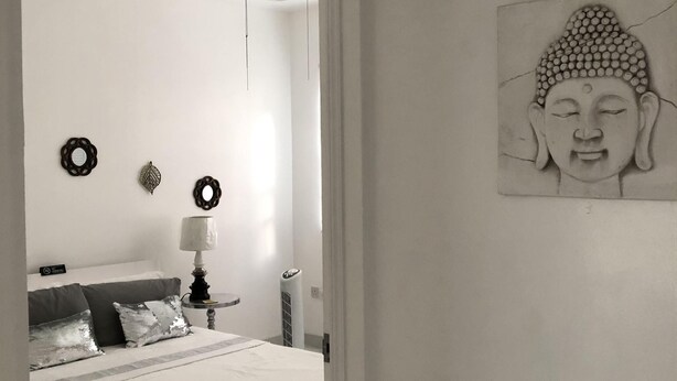 Camera da letto dal design minimalista con letto, comodino, lampada e decorazioni a parete.