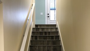 A staircase with wooden steps and white handrails, leading to a door with a light blue wall. - Located at Silver Lake with access to Silver Lake and sand dunes. (Mears)