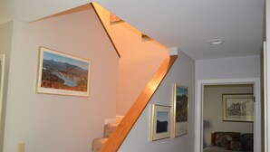 Una escalera con escalones de madera y un cuadro colgado en la pared que muestra un paisaje.