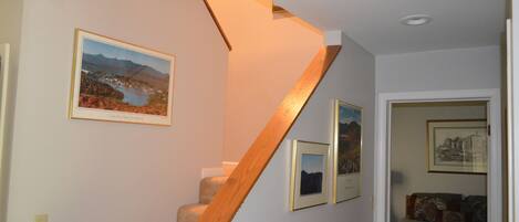 A staircase with wooden steps and a wall-mounted picture of a landscape.