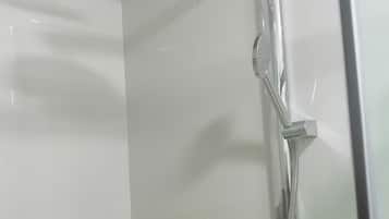 Ducha con cabezal de ducha de lluvia y un cabezal de ducha manual, un perchero y un panel de madera en la pared.
