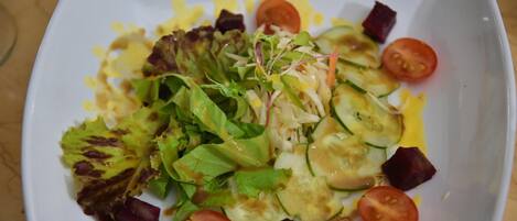 A white square plate with a salad consisting of lettuce, cucumber, tomato, and beetroot slices.