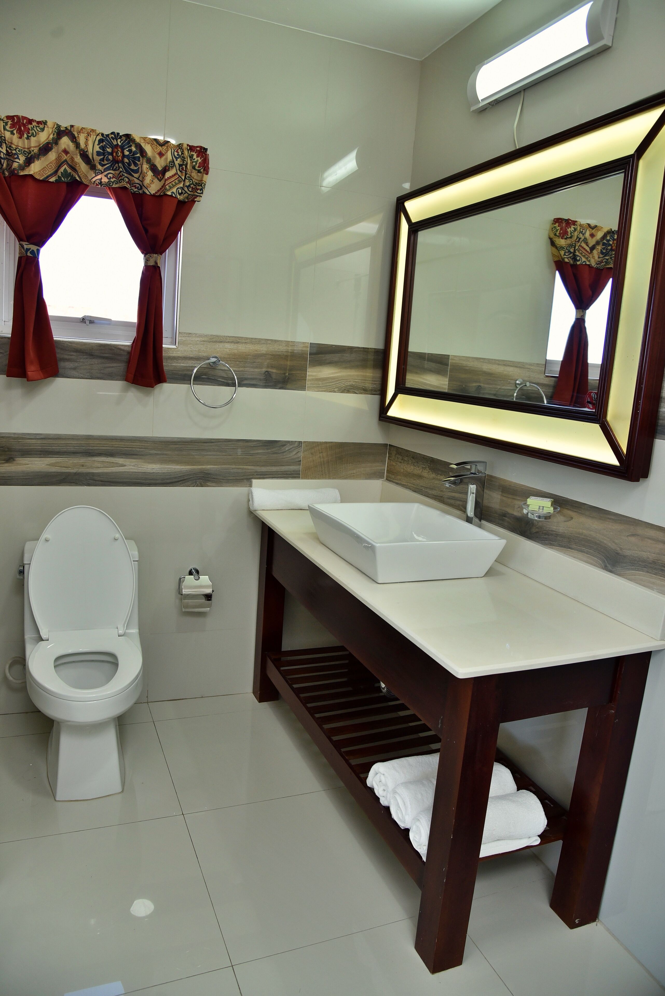 A modern bathroom with a white toilet, a rectangular sink, and a mirror above the sink.