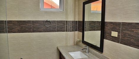 A bathroom with a sink, mirror, and window.