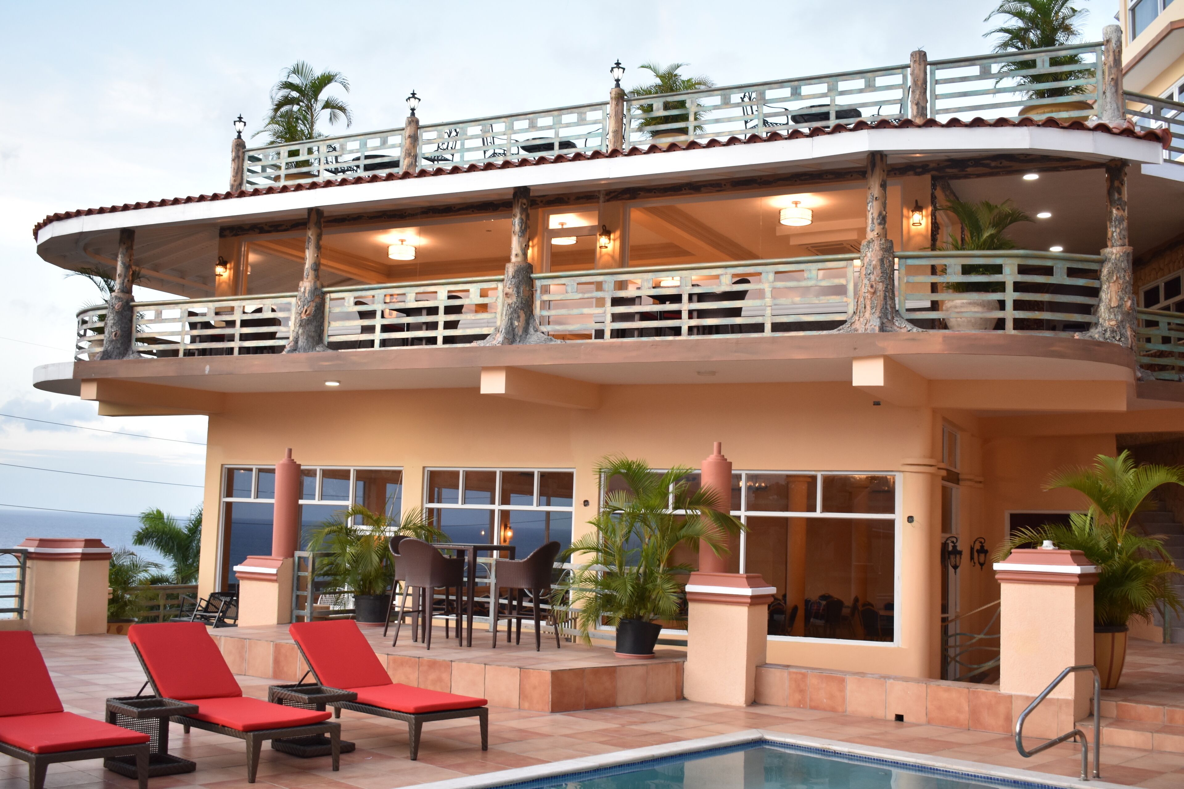 A hotel with a pool area, outdoor seating, and a view of the ocean.