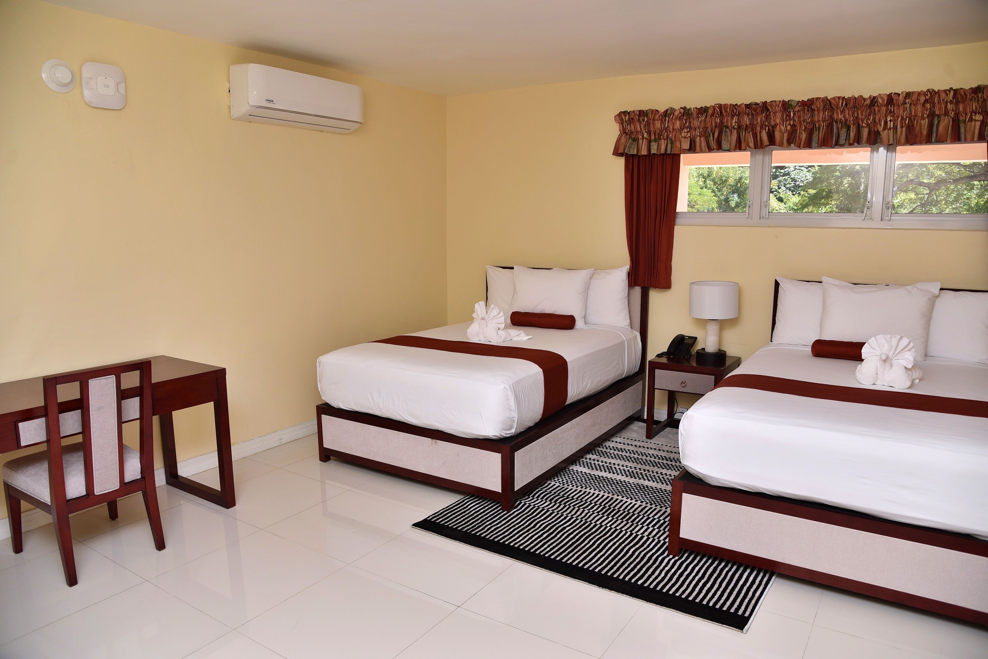 A hotel room with two beds, a desk, and a chair.