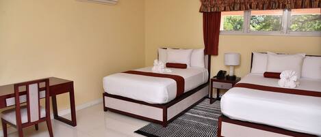 A hotel room with two beds, a desk, and a chair.