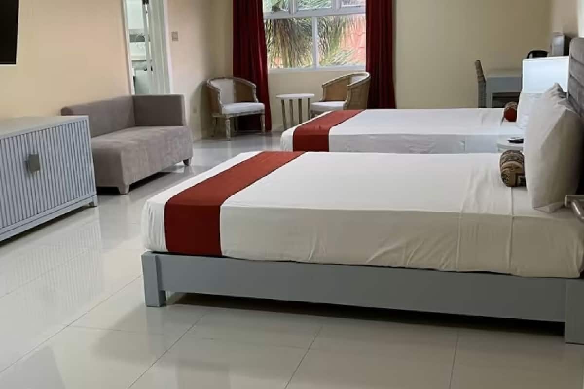 Habitación de hotel con dos camas, un sofá, un televisor y una ventana con vistas.