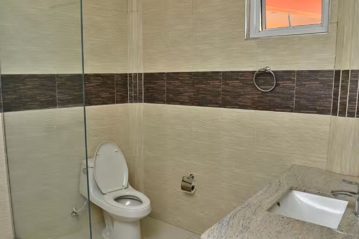 A bathroom with a toilet, a sink, and a window.