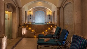 A spa area with a mosaic-tiled wall, two lounge chairs, and a small seating area with candles.