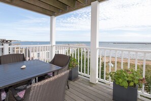 A covered outdoor area with a table and chairs, a view of the sea, and potted plants. - Beachfront, East End, 2 BR, 2BA, Private Deck, Parking, Dog Friendly (Provincetown)