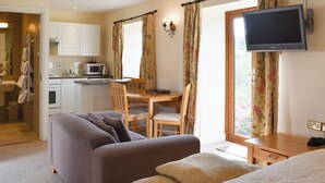 Een hotelkamer met een bed, een bank, een eettafel met stoelen, een aan de muur bevestigde televisie en een kitchenette.
