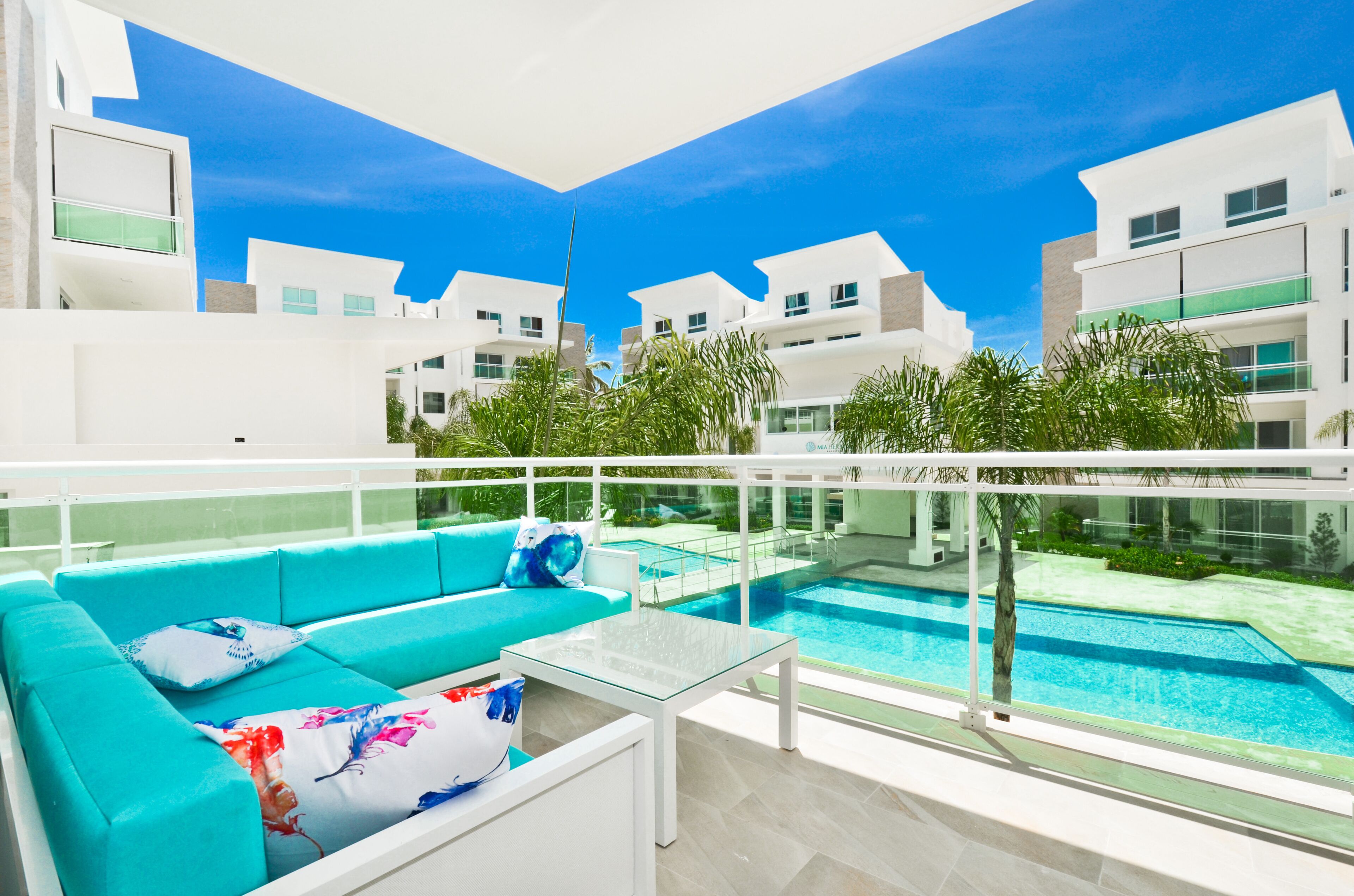 A modern apartment with a balcony, a pool, and a view of other buildings.