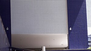 Un escalier en colimaçon avec des rampes en métal et un mur recouvert de carreaux.