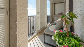 A balcony with a sofa, a potted plant, and a view of the cityscape. - Cozy apartment in Zadar with WiFi (Zadar)
