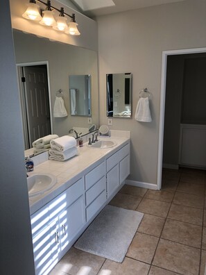 Une salle de bain moderne avec un meuble-lavabo à deux vasques, un grand miroir et un porte-serviettes.