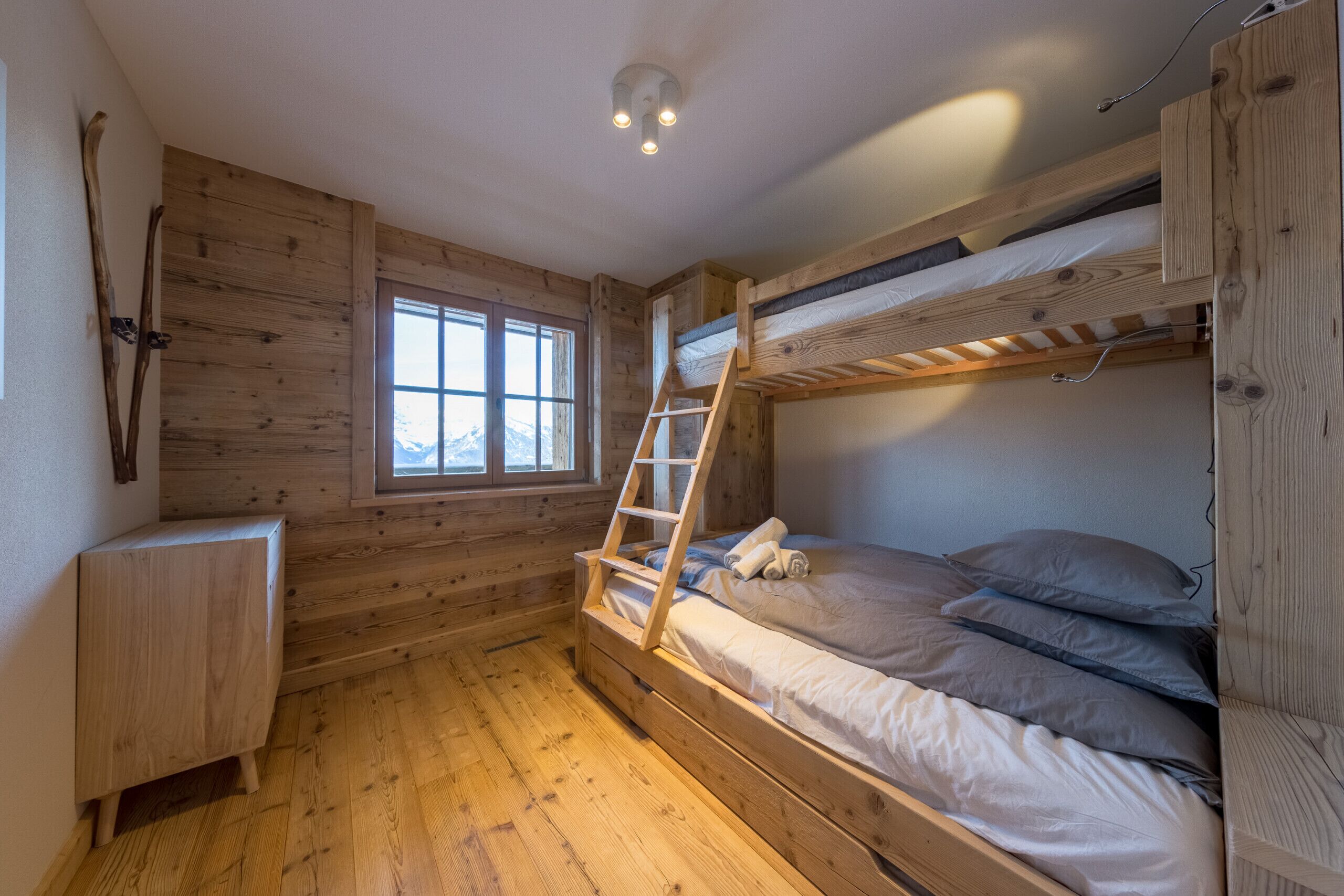 Ein Zimmer in einer Holzhütte mit Etagenbetten, einer Himmelsleiter und einem Fenster.