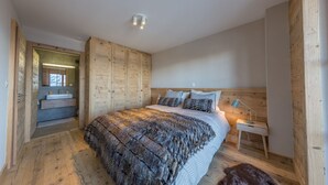 Ein Schlafzimmer mit einem großen Bett, einem Holz-Kopfteil, einem Nachttisch und einem kleinen Fenster.