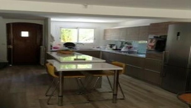 A modern kitchen with a central island, stainless steel appliances, and wooden flooring. - VILLA CAROLINA T4 (Montpellier)