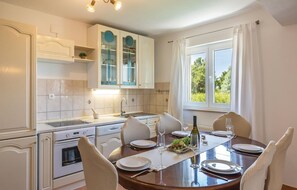 Enjoy meals in the well-appointed kitchen and dining area, featuring an oven, stainless steel sink, and a round table for four.