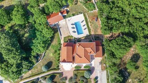 Vista aerea di una proprietà con piscina, patio coperto e giardino curato.