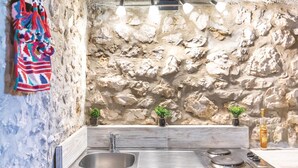 Una cucina con parete di pietra a rivestimento, lavello in acciaio inossidabile e piano cottura a gas.