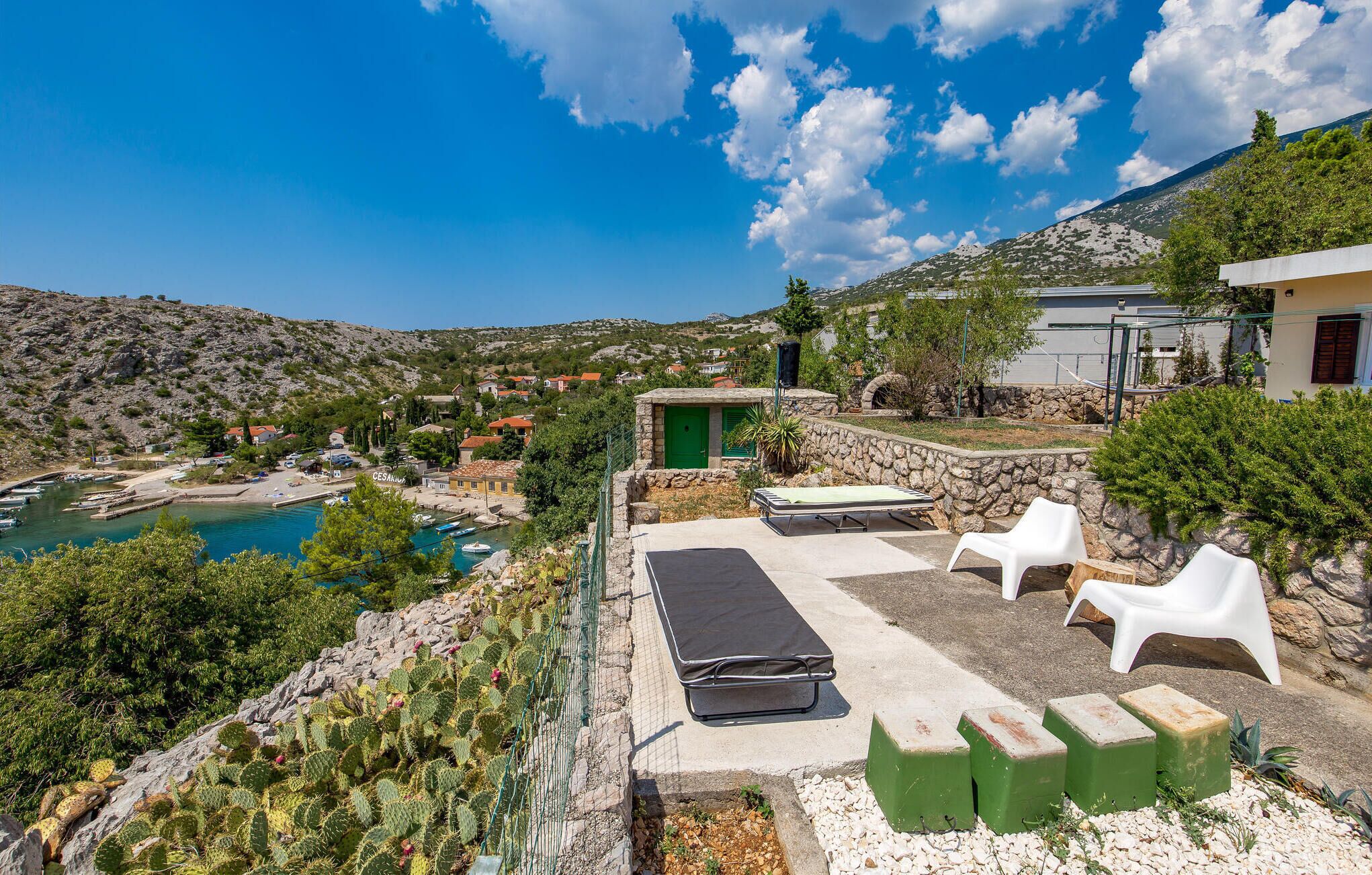 A coastal property with a pool, outdoor seating, and a view of the sea and hills.
