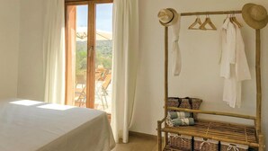 A bedroom with a bed, a window with curtains, a wooden rack with clothes and baskets, and a view of the outdoors. - Lovely home in Son Carrió with WiFi (Son Carrió)
