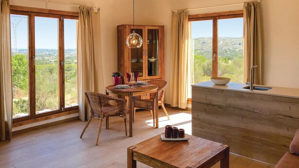 A dining area with a round table, wicker chairs, and a cabinet with glass doors. - Lovely home in Son Carrió with WiFi (Son Carrió)