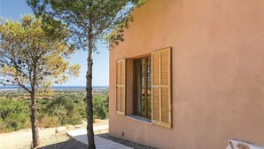 A building with a window and shutters, a tree in front, and a view of the landscape. - Lovely home in Son Carrió with WiFi (Son Carrió)