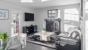 A modern living room with a fireplace, a flat-screen TV, a sofa, and a coffee table.