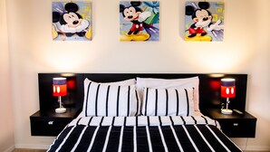 A bed with black and white striped bedding, two Mickey Mouse themed nightstands, and three Mickey Mouse themed wall art pieces. - Lake View 3 Bedroom Villa. Enjoy Private Hot Tub! (Kissimmee)